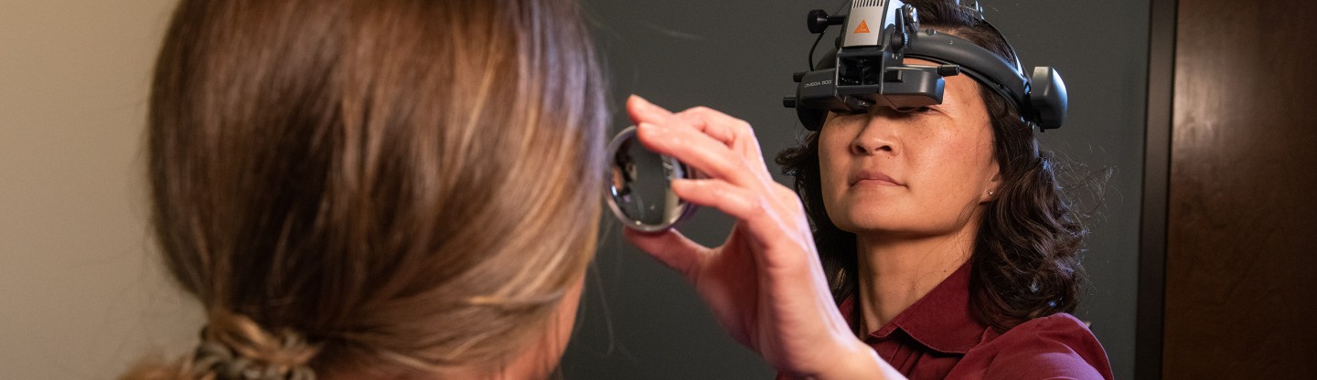 dr lee uses an ophthalmoscope on a female patient during an eye exam spokane eye clinic