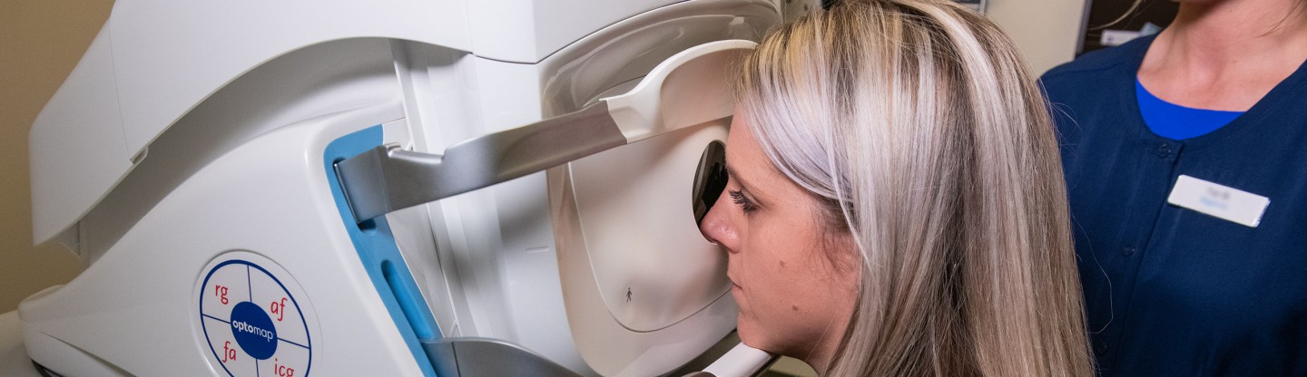 a female patient looks into an optomap imaging machine during an eye exam spokane eye clinic